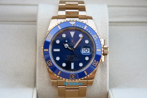 Rolex 116618LB | SD Watches Gold Rolex Submariner watch with a blue bezel resting on a light display cushion.