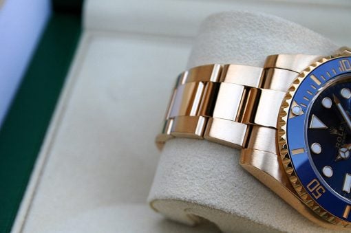 IMG_6482 | SD Watches Close-up of a gold Rolex watch with a blue bezel and metal link bracelet resting on a padded display pillow.