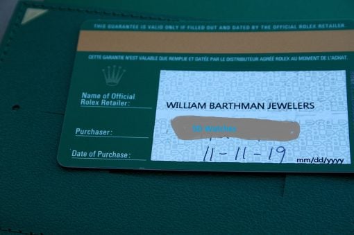 IMG_6488 | SD Watches Close-up of a green Rolex warranty card showing the retailer name 'William Barthman Jewelers' and a masked approval area labeled 'SD Watches' on a patterned background.