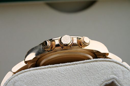 IMG_6522 | SD Watches Close-up of a gold Rolex watch crown and side pushers resting on a soft white towel, with the crown logo visible.