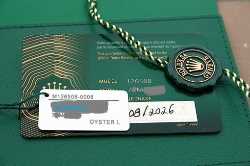IMG_6528 | SD Watches Close-up of a green Rolex card with a braided green-and-gold string and a circular Rolex seal.