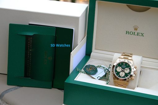 IMG_6529 | SD Watches Open green Rolex box displaying a gold Rolex watch with green dial and white subdials, plus green warranty tag and booklets nearby.