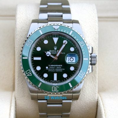 Rolex 116610LV | SD Watches Green-bezel Rolex Submariner with stainless steel bracelet on a beige cushion display