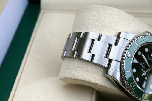 IMG_6544 | SD Watches Close-up of a stainless steel Rolex watch bracelet resting on a beige display cushion, with part of a green bezel visible.