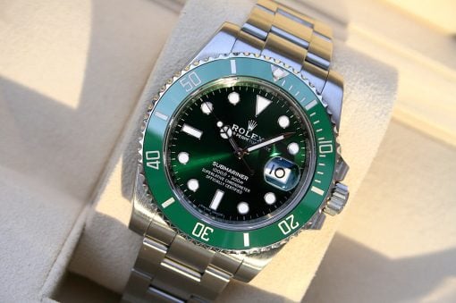 IMG_6561 | SD Watches Close-up of a Rolex Submariner dive watch with a green bezel and black dial on a beige surface.