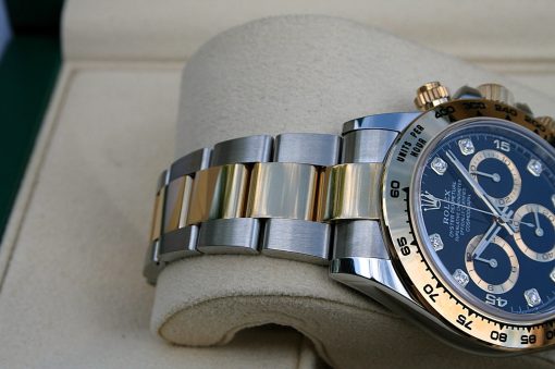 IMG_6680 | SD Watches Close-up of a two-tone (silver and gold) Rolex wristwatch with a blue dial resting on a beige cushion; prominent bezel and diamonds on dial edges visible.