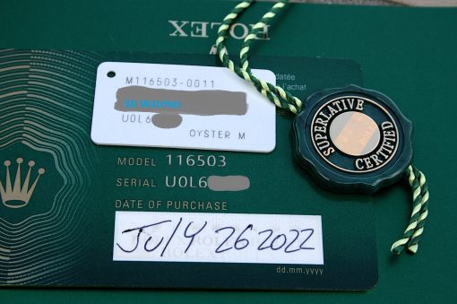 IMG_6686 | SD Watches Close-up of a Rolex authenticity card showing model 116503 and a handwritten purchase date of 7/14/2022, with a green warranty card and tag in view.