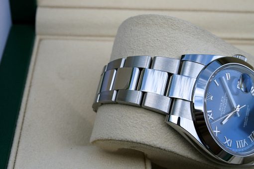 IMG_6698 | SD Watches Close-up of a silver Rolex Datejust watch with a blue dial and Roman numeral markers on a beige display cushion.