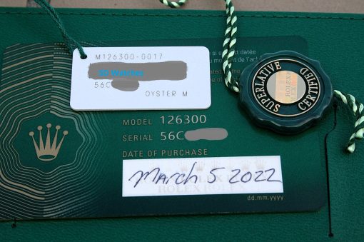 IMG_6703 | SD Watches Close-up of a Rolex tag on a green box, showing model number 126300 and a circular Rolex seal; label reads 'SD Watches'.
