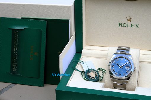IMG_6704 | SD Watches Rolex wristwatch in an open beige box with a stainless steel bracelet and a blue dial, beside the green outer box and tags.