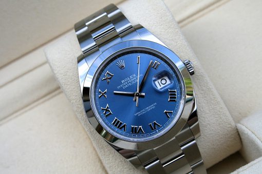 IMG_6705 | SD Watches Close-up of a Rolex Oyster Perpetual Datejust wristwatch with a blue dial, Roman numeral hour markers, and a magnified date window at 3 o'clock on a metallic bracelet.