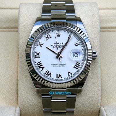 Rolex Datejust wristwatch with a white dial, Roman numerals, and a fluted bezel displayed on a beige cushion.