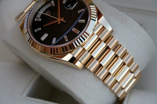 IMG_6732 | SD Watches Close-up of a gold luxury wristwatch with a black face and diamond markers on a light fabric surface.