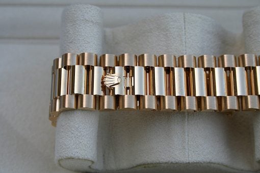 IMG_6734 | SD Watches Close-up of a gold-tone metal link bracelet with a Rolex clasp showing the crown logo on a padded display surface