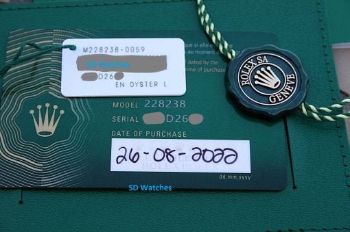 IMG_6741 | SD Watches Close-up of a Rolex authenticity card with a white label reading 'SD Watches' and a green Rolex seal attached by a cord.