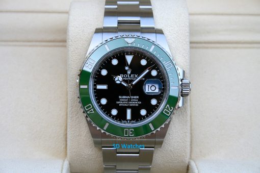 Rolex 126610LV | SD Watches Rolex Submariner stainless steel watch with black dial and green bezel resting on a beige cushion, showing the date at 3 o'clock with a magnifier.