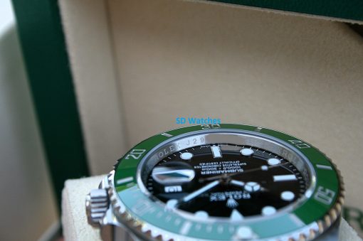 IMG_6786 | SD Watches Close-up of a Rolex watch with a green bezel and black dial, angled in a box.