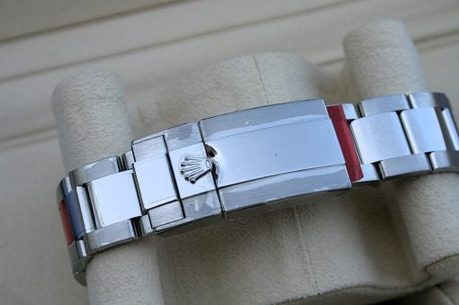 IMG_6827 | SD Watches Close-up of a stainless steel Rolex bracelet with its crown-clasp, lying on a beige padded surface/glove.