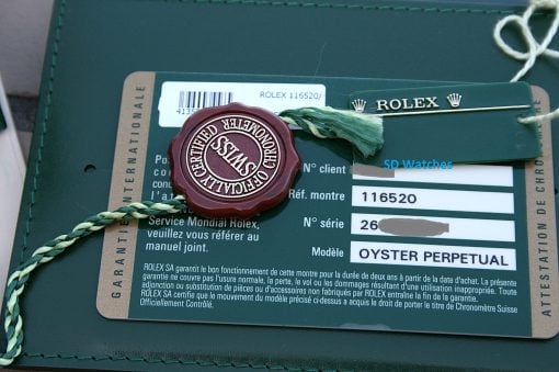 IMG_6834 | SD Watches Close-up of a Rolex authenticity card with a green tag and red seal attached by a green cord.