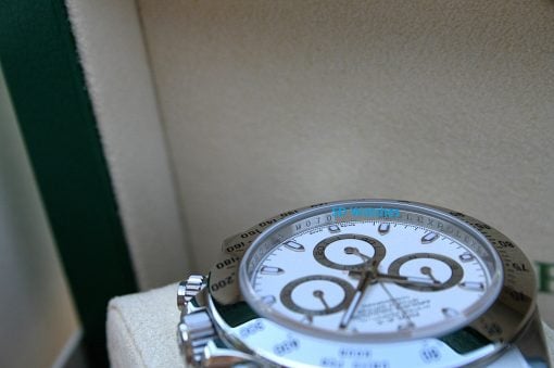IMG_6853 | SD Watches Close-up of a silver chronograph wristwatch with a white dial and a numbered bezel, resting on a soft beige surface; blue watermark reads 'SD Watches'.