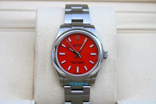 Rolex 277200 Red Coral | SD Watches Close-up of a stainless steel Rolex watch with a bright red dial on a cushioned display lapel/stand, showcasing the bracelet and bezel.
