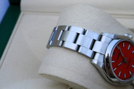 IMG_6759 | SD Watches Close-up of a stainless steel watch band resting on a beige cushion with a bright red watch face partially visible.
