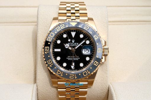 Rolex 126718 | SD Watches Gold Rolex GMT-Master II wristwatch with black dial on beige display cushion, gold bezel and bracelet