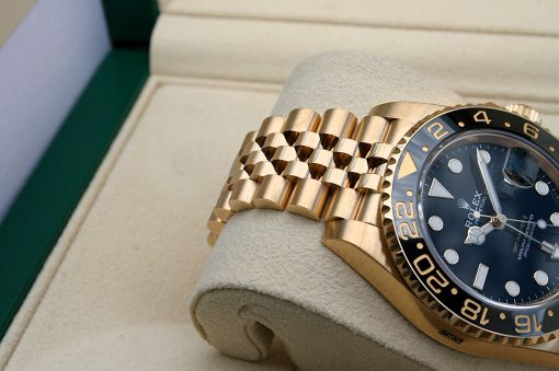 IMG_6895 | SD Watches Close-up of a gold Rolex watch with a black bezel resting on a beige padded display cushion