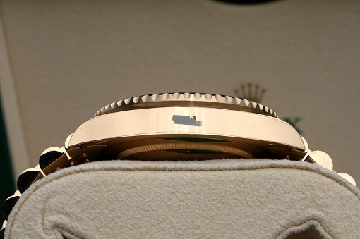 IMG_6896 | SD Watches Close-up of a gold-tone wristwatch with a knurled rotating bezel, resting on a soft beige cushion surface.