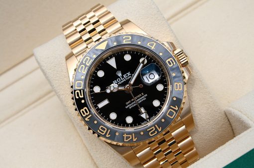 IMG_6903 | SD Watches Gold Rolex GMT-Master II watch with black dial and date magnifier, resting on a beige display cushion; polished gold bracelet visible.