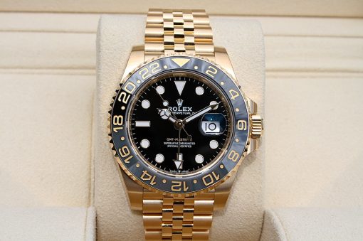 IMG_6904 | SD Watches Gold Rolex GMT-Master II wristwatch with a black dial and blue-bezel, placed on a beige display cushion.