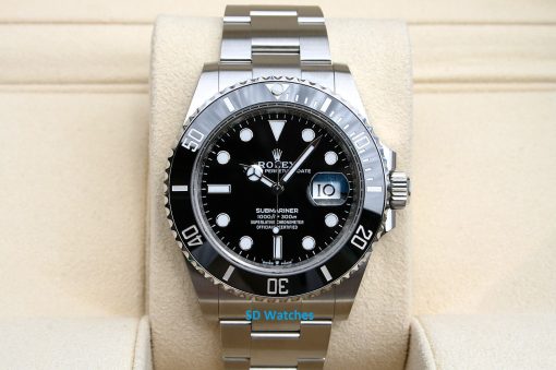 Rolex 126610 | SD Watches Close-up of a stainless steel Rolex Submariner watch with black dial on a beige display cushion, showing date magnifier.