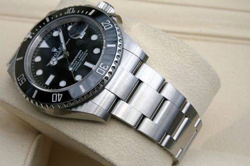 IMG_6911 | SD Watches Close-up of a stainless steel Rolex Submariner wristwatch with a black dial on a beige cushion.