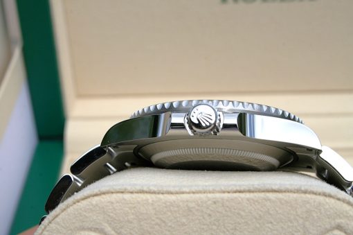 IMG_6914 | SD Watches Close-up of a polished watch crown with fluted edge on a shiny metal case resting on a beige fabric surface
