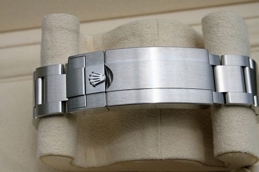 IMG_6915 | SD Watches Close-up of a stainless steel Rolex Oyster bracelet clasp with the crown logo on a beige display pillow