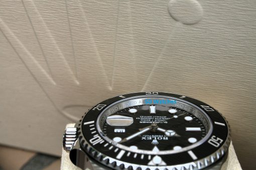 IMG_6917 | SD Watches Close-up of a black Rolex dive watch with a textured bezel, displayed on a beige surface; blue 'SD Watches' watermark across the face.