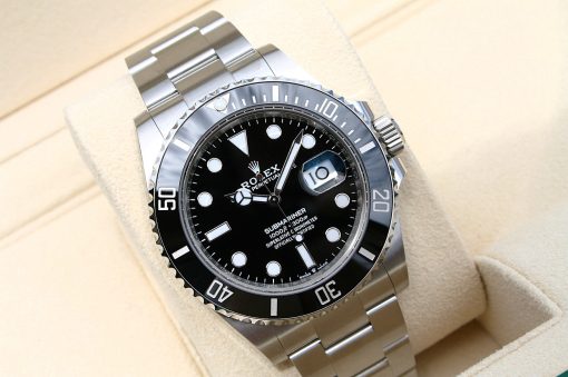IMG_6920 | SD Watches Close-up of a stainless steel Rolex Submariner wristwatch with a black dial and rotating bezel, resting on a beige cushion.