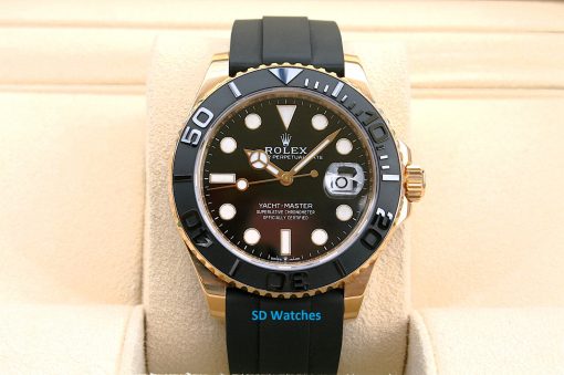 Rolex 226658 | SD Watches Rolex Yacht-Master watch with a black dial, gold bezel and black rubber strap on a beige display cushion.