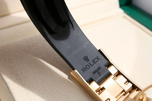 IMG_6937 | SD Watches Close-up of a metal Rolex watch bracelet clasp with the ROLEX engraving on a dark strap, resting on a beige surface.