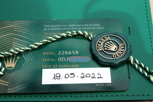 IMG_6938 | SD Watches Close-up of a Rolex warranty card with the Rolex seal and a green-and-cream braided cord laid across it.
