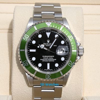 Rolex Submariner diver's watch with a green bezel and black dial on a beige display pillow