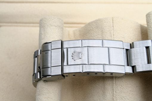 IMG_6949 | SD Watches Close-up of a stainless steel Rolex watch bracelet clasp with the Rolex crown logo visible on a beige display cushion