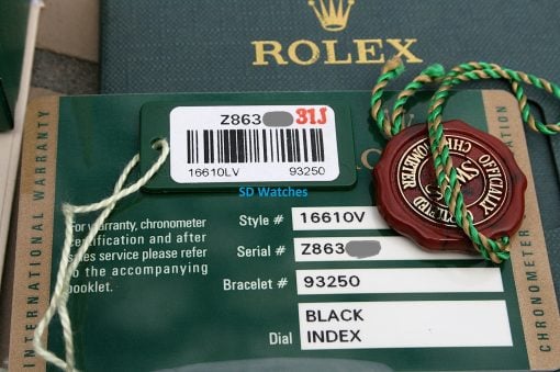 IMG_6950 | SD Watches Close-up of Rolex warranty tags: barcode label on green card, red seal, and braided green-tan cord laid over the paperwork.