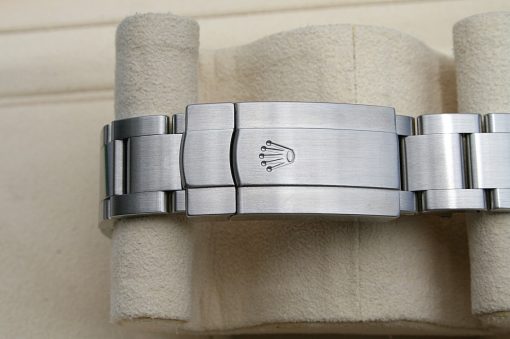 IMG_6968 | SD Watches Close-up of a stainless steel Rolex Oyster bracelet with a clasp bearing the Rolex crown logo on a beige display pillow.