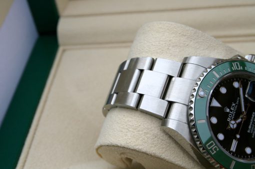 IMG_7075 | SD Watches Close-up of a stainless steel Rolex dive watch with a green bezel resting on a beige cushion inside a display box.