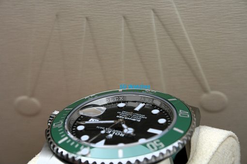 IMG_7077 | SD Watches Close-up of a Rolex Submariner watch with a green bezel and black dial on a white cloth surface