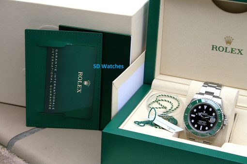 IMG_7082 | SD Watches Rolex watch with a green bezel in its green presentation box next to a warranty card and papers.