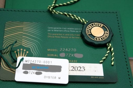 IMG_7098 | SD Watches Close-up of a green Rolex warranty card with a black circular 'Superlative Certified' seal and green-gold braided string attached.