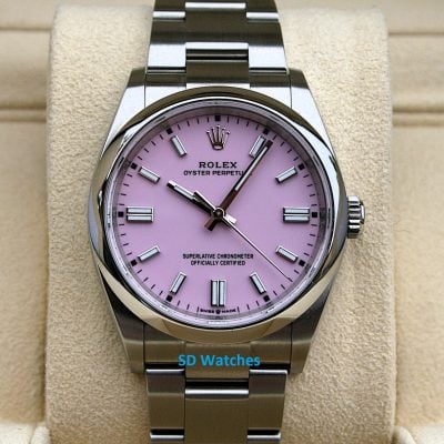 Rolex Oyster Perpetual watch with a pink dial on a metal bracelet, displayed on a beige cushion.