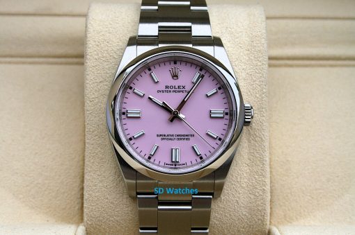 Rolex 126000 Candy | SD Watches Rolex Oyster Perpetual watch with a pink dial on a metal bracelet, displayed on a beige cushion.